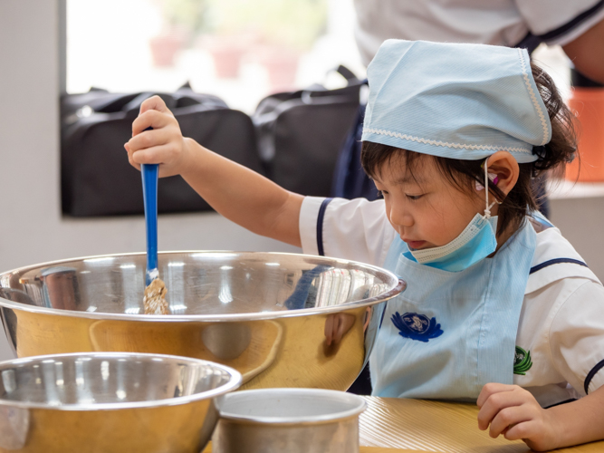 After getting instruction, preschooler tries to mix ingredients on her own. 【Photo by Daniel Lazar】
