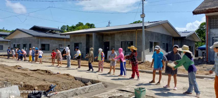 Nothing is impossible when we work together: Palo beneficiaries pass cement tiles to lay on the front of permanent homes in Tzu Chi Great Love Village. 