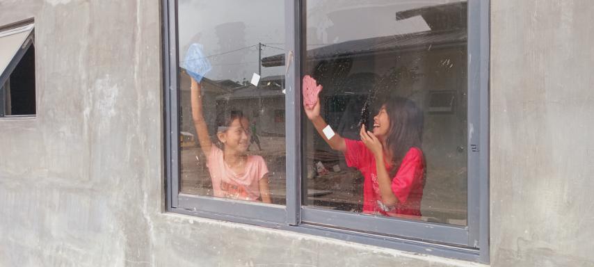 Young girls help wipe windows and doors.