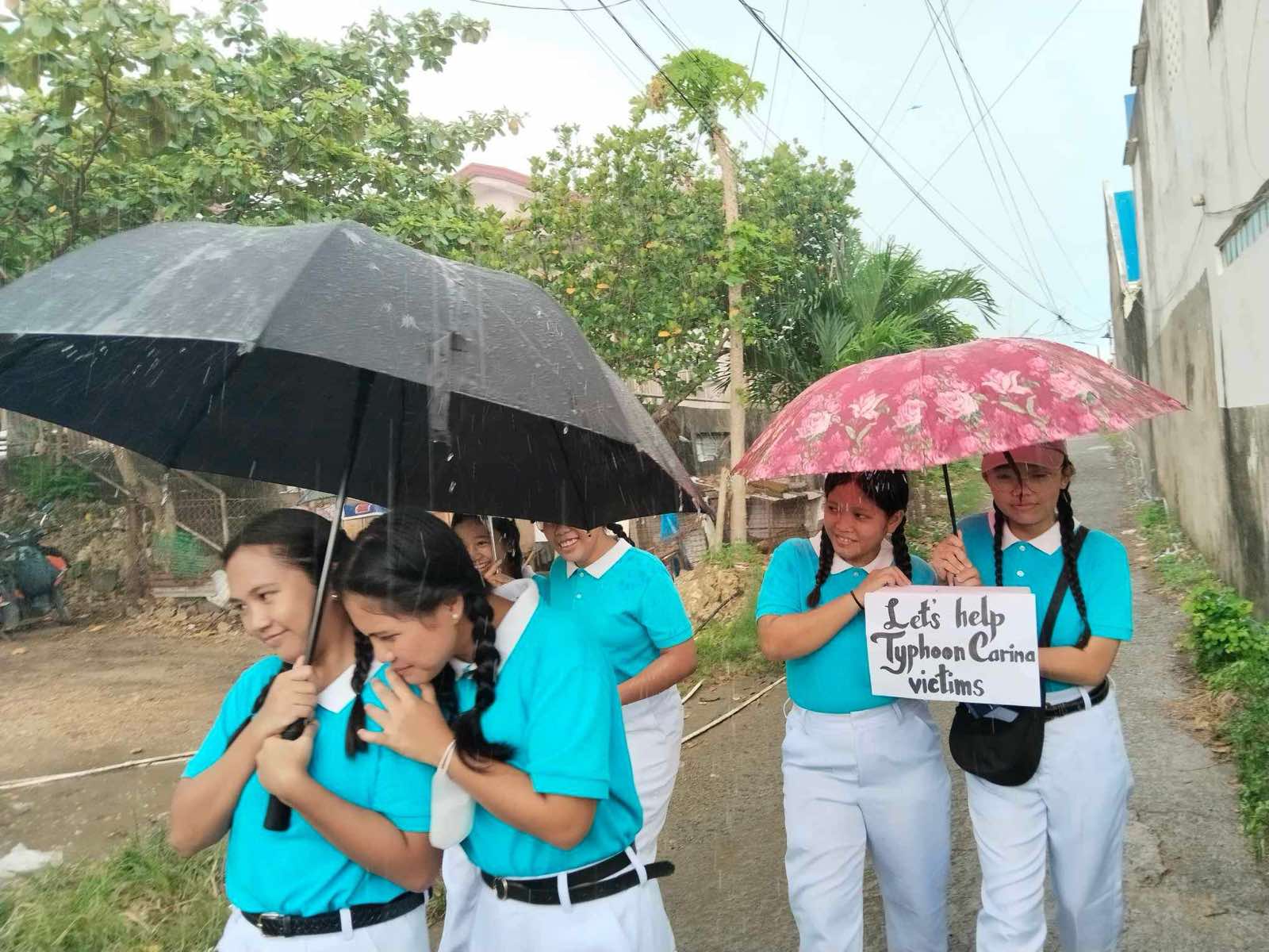 Tzu Chi Cebu scholars brave the rain as they go from house to house in their neighborhood of Pulpogan, collecting donations for victims of Typhoon Carina (Gaemi). 