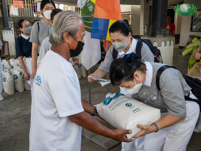 Volunteer bows as she hands out 10 kilos of rice to beneficiary. 【Photo by Kendrick Yacuan】