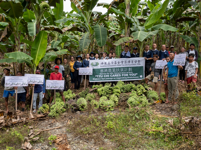 Tzu Chi volunteers gather for a group photo alongside farmers proudly displaying their banana harvests. 【Photo by Matt Serrano】